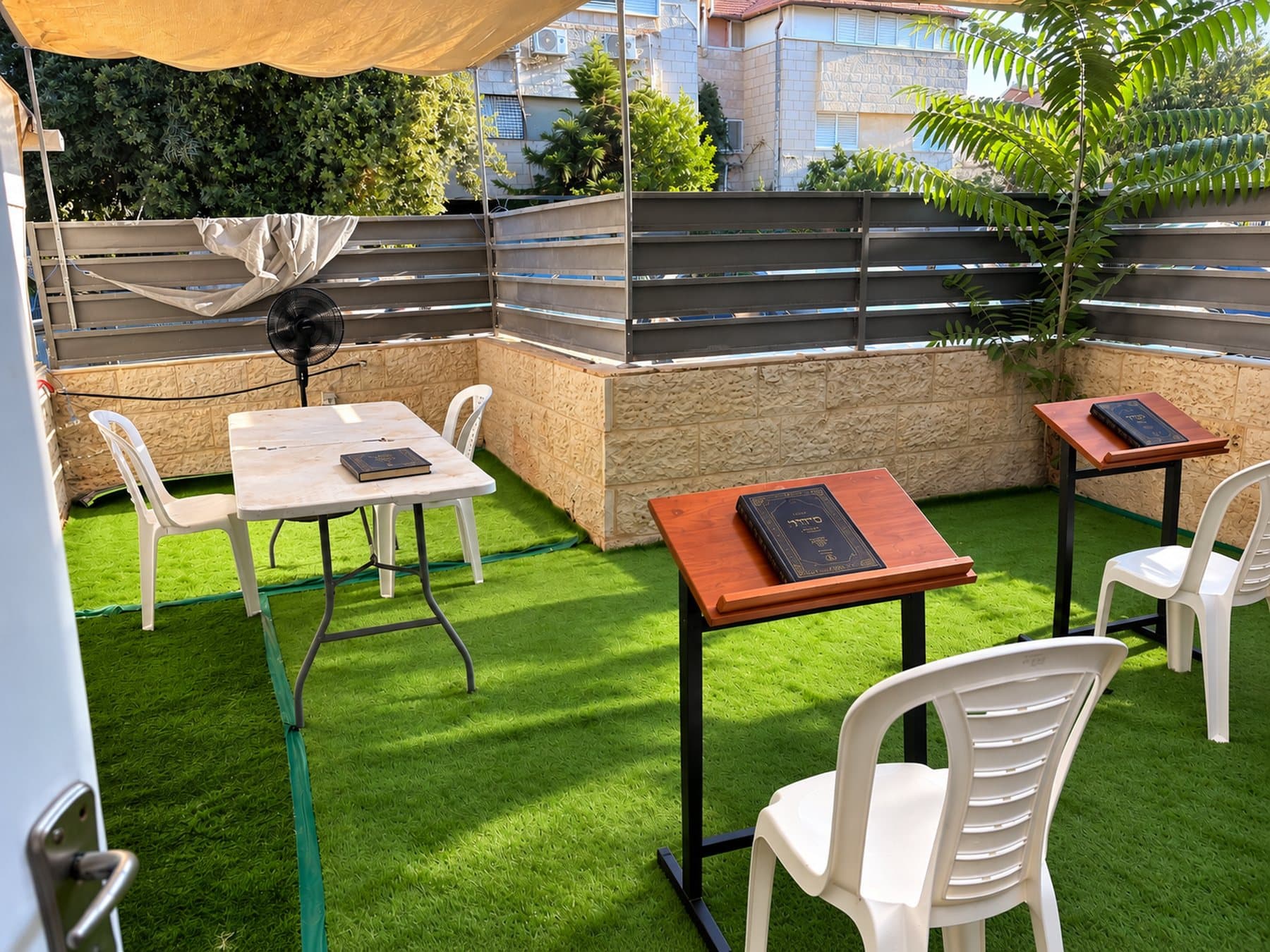 The outdoor minyan and learning space beside the Beis Medrash, with tables, shtenders and chairs